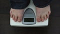 Overweight male feet on weighing scales, measuring kilograms after workout