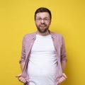 Overweight man holding his shirt showing his extra belly fat and smirking contentedly. Concept of proper nutrition and Royalty Free Stock Photo