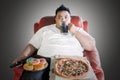 Overweight man with junk foods during watch TV Royalty Free Stock Photo