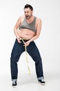 Overweight man looking at camera and measuring waistline with tape on white Royalty Free Stock Photo