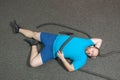 Overweight man is lying on the floor exhausted after performing battle rope exercise in the fitness gym Royalty Free Stock Photo