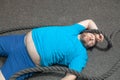 Overweight man is lying on the floor exhausted after performing battle rope exercise in the fitness gym Royalty Free Stock Photo