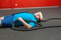 Overweight man is lying on the floor exhausted after performing battle rope exercise in the fitness gym Royalty Free Stock Photo