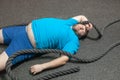 Overweight man is lying on the floor exhausted after performing battle rope exercise in the fitness gym Royalty Free Stock Photo