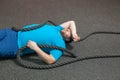 Overweight man is lying on the floor exhausted after performing battle rope exercise in the fitness gym Royalty Free Stock Photo