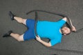 Overweight man is lying on the floor exhausted after performing battle rope exercise in the fitness gym Royalty Free Stock Photo