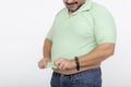 An overweight man struggles to cover his belly with an undersized polo shirt that used to fit him. A shirt too small or