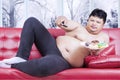 Overweight man watching tv and eats donuts Royalty Free Stock Photo