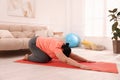 Overweight mature woman doing exercise on yoga mat at home