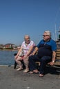 An overweight middle aged couple sitting on a park bench