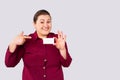 Overweight positive obese woman showing blank business card, empty credit card on grey background. Close up with side