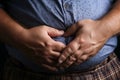 Overweight reality mans hand holds belly fat, depicting health concerns