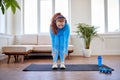 overweight redhead woman doing stretching exercise at home, standing on fitness mat Royalty Free Stock Photo