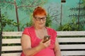 Overweight redheaded old woman looking at his cell phone Royalty Free Stock Photo
