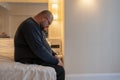 Overweight sad man resting alone in hotel having midlife crisis sitting on bed and boring.