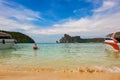 Overweight woman in a bathing suit comes into the sea for swimming. View on Phi Phi islands, sandy beach with waves and blue