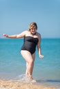 Overweight woman in black one-piece swimsuit comes from sea Royalty Free Stock Photo