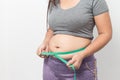 Overweight woman check out his body fat with green measuring tape for obesity on gray background Royalty Free Stock Photo