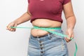 Overweight woman check out his body fat with green measuring tape for obesity on gray background, Royalty Free Stock Photo
