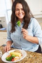 Overweight Woman Eating Healthy Meal In Kitchen Royalty Free Stock Photo