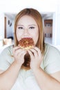 Overweight woman eats donut at home Royalty Free Stock Photo