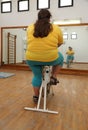 Overweight woman exercising on bike simulator