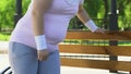 Overweight woman exhausted after tiresome workout outdoors, resting on bench