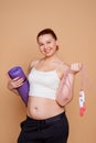 Overweight woman getting in shape. She`s holding a rolled mat and a jump rope