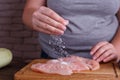 Overweight woman hands adding salt to raw chicken breasts. Dieti Royalty Free Stock Photo