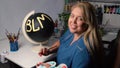 Overweight woman painting BLM sign on the black globe