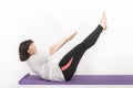 Overweight woman plays sports on yoga mat. Girl rocks the abs. Side view on white background Royalty Free Stock Photo