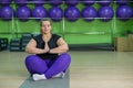 Overweight woman practices yoga in the gym. Calm and zen fat girl in lotus position.