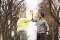 An overweight woman running in nature with friend, high five. Exercising outdoors for people with obesity, support from Royalty Free Stock Photo