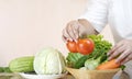 Woman hand preparing various fresh vegetables into bamboo basket for cooking in kitchen area Royalty Free Stock Photo