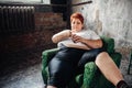 Overweight woman sits in a chair and eats sweets Royalty Free Stock Photo