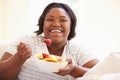 Overweight Woman Sitting On Sofa Eating Bowl Of Fresh Fruit Royalty Free Stock Photo