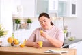 Overweight woman squeezing orange juice into glass at table in kitchen Royalty Free Stock Photo