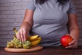 Overweight woman taking some grapes from the dish. Dieting, usef