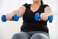 Overweight woman training with dumbbells