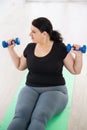 Overweight woman training with dumbbells