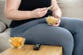 Overweight woman with tv remote and junk food