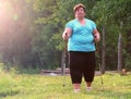 Overweight woman walking on forest trail.