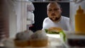 Overweight young man opening fridge at night to take big burger, calories Royalty Free Stock Photo