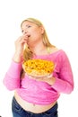 Overweight young woman eating from bowl of crisps Royalty Free Stock Photo