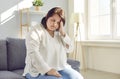 Overweight young woman with headache sitting on sofa at home