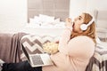 Overweight young woman with headphones on unpleasantly eating