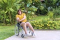 Overweight young woman sitting alone on the wheelchair while her hands are sinking due to nervous system illness,