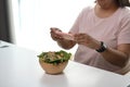 Overweight young woman using smartphone taking photo vegetable salad.