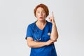 Overwhelmed redhead female doctor, middle-aged nurse in scrubs have suggestion, saying idea or plan, raising index Royalty Free Stock Photo