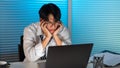 Overwork Concept The man in the office resting his face on his hands and staring at the laptop screen Royalty Free Stock Photo
